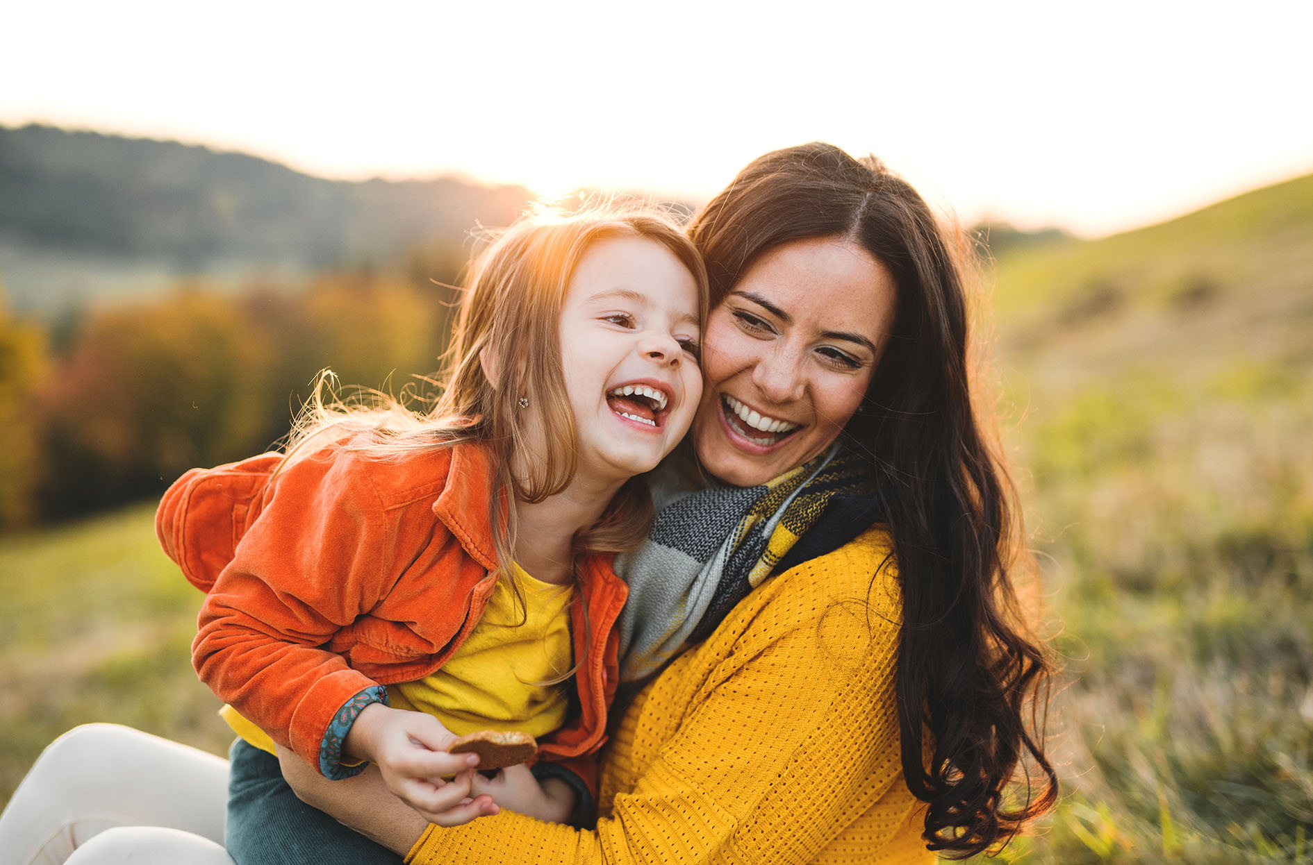 Young mother with a small daughter in autumn nature at sunset